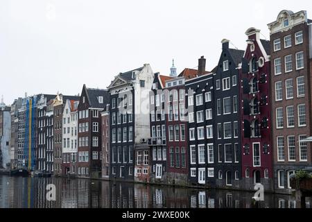 Schiefe Häuser an Amsterdams Uferpromenade spiegeln sich in den Kanälen, der historischen Architektur der Stadt in der niederländischen Hauptstadt, wider Stockfoto