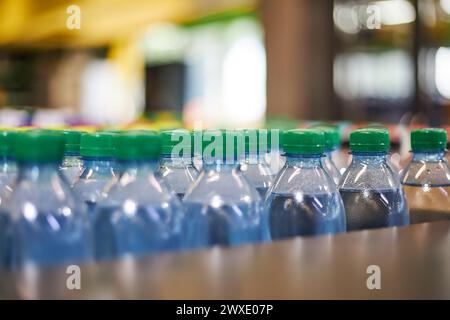 Blaue halbstündige Mineralwasser-Flaschen aus Kunststoff mit grünem Verschluss im Lager, Supermarktregel, Nahaufnahme. Hoher Kunststoffverbrauch im Alltag, was die Umwelt belastet Stockfoto