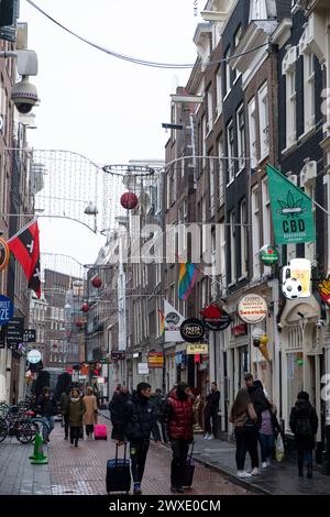 Niederlande, Amsterdam, Januar 2020. Festliche Straße in Amsterdam mit vielen Schildern und Anzeigen. Touristenmassen gehen einkaufen und besuchen Cafés. Stockfoto