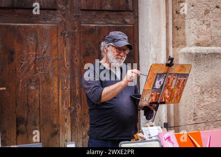 Palma de Mallorca, Spanien - 29. April 2023: Straßenkünstler, der an der Malerei der Leinwand im touristischen Zentrum einer geschäftigen Stadt auf den Balearen arbeitet Stockfoto
