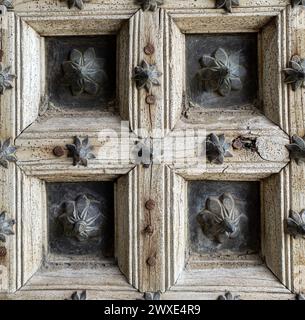 Fragment einer antiken alten Tür aus hellem, unbemaltem Holz und Metallmaterialien mit Blumenmuster, Nahaufnahme. Elemente der Architektur alter Gebäude, Fensterläden Stockfoto