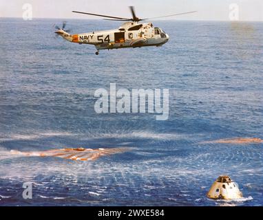 Unmittelbar nach dem Spritzen schwebt ein Rettungshubschrauber der USS Guadalcanal über dem Raumschiff Apollo 9. Im Command Module (cm) befinden sich noch die Astronauten James A. McDivitt, David R. Scott und Russell L. Schweickart. Splash-down fand am 13. März 1969 um 12:00:53 Uhr (EST) statt. Nur 4,5 Seemeilen von der USS Guadalcanal entfernt, dem besten Bergungsschiff, um eine erfolgreiche 10-tägige Erdumlaufmission im Weltraum zu beenden. Eine optimierte und verbesserte Version eines Originalbildes der NASA/obligatorischer Kredit: NASA Stockfoto