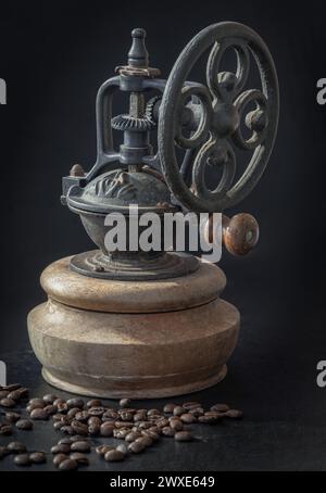 Antike Kaffeebohne Original Mahlwerk Metall Shake Wheel mit Handkurbel und Kaffeebohnen auf dunklem Hintergrund. Alte originale Kaffeemühle mit Spuren von Stockfoto