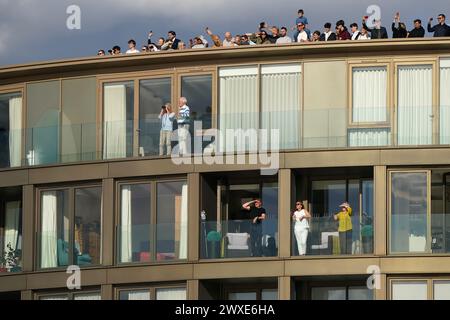 Zuschauer beobachten aus nahe gelegenen Gebäuden beim 169. Men's Gemini Boat Race 2024 auf der Themse in London. Bilddatum: Samstag, 30. März 2024. Stockfoto