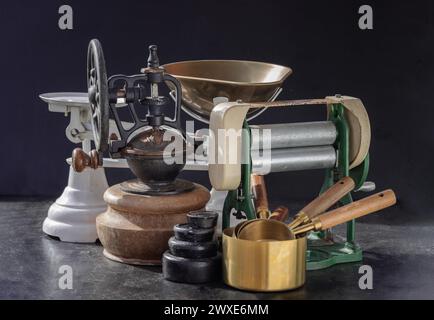 Die antike Kollektion verfügt über eine Nudelmaschine mit Handkurbel, eine originale Kaffeemühle aus Metall mit Handkurbel, eine Waage und Messbecher aus Messing Stockfoto