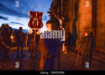 Ein Altarjunge trägt ein Kreuz mit Kürbis während der Karfreitagsprozession in San Vicente de la Sonsierra. Hunderte Gläubige kamen am Karfreitag in die Kirche San Vicente de la Sonsierra in La Rioja, Spanien, um die Prozession von Los Picaos zu beobachten. Stockfoto