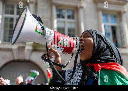 The Strand, London, Großbritannien. 30. März 2024. Während der Konflikt zwischen Israel und der Hamas anhält, findet ein Protest gegen die Eskalation der militärischen Aktionen im Gazastreifen statt. Organisiert von Gruppen wie der palästinensischen Solidaritätskampagne und der „Stop the war Coalition“ mit dem Titel „nationale Demonstration“ und mit Aufrufen zu „Stop the Genocide“, „Ceasefire Now“ und „Free Palestine“, brachen die Demonstranten vom Russell Square auf, bevor sie zum Trafalgar Square fuhren. Frauengesang durch Megaphon Stockfoto