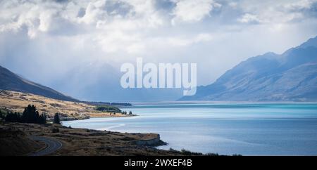 Alpine Landschaft mit azurblauem See, Sonnenlicht und dicken Wolken herannahender Sturmwolken. Stockfoto