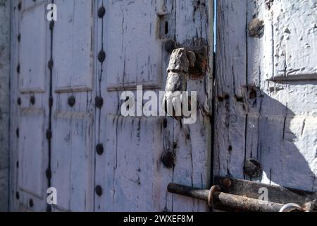 Seitenansicht des Klopfers einer alten blau lackierten Holztür mit rostigen Eisenbeschlägen und Schlossansicht des Klopfers einer alten blau lackierten Holztür Stockfoto