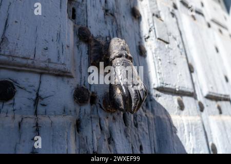 Nahaufnahme von unten auf den Klopfer einer alten blau lackierten Holztür mit rostigen Eisenbeschlägen und Schlossansicht des Klopfers einer alten blauen p Stockfoto