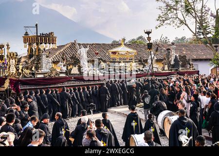 Antigua, Guatemala. März 2024. Katholische Pönitenten tragen den massiven Senor Sepultado-Prozessionszug zu Beginn der Karfreitagsprozession während der Semana Santa, 29. März 2024 in Antigua, Guatemala, durch das historische Stadtzentrum. Die opulente Prozession ist eine der größten der Welt und erfordert über 100 Personen, um den Wagen zu tragen. Die Prozession dauert 12 Stunden. Quelle: Richard Ellis/Richard Ellis/Alamy Live News Stockfoto