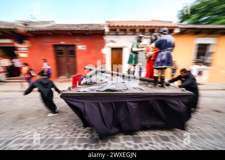 Antigua, Guatemala. März 2024. Katholische Pönitenten Rollen einen Prozessionswagen, der Teil einer Serie der letzten Momente Christi ist, während sie sich auf die Karfreitagsprozession des Senors Sepultado Escuela de Cristo während der Semana Santa am 29. März 2024 in Antigua, Guatemala, vorbereiten. Die opulente Prozession ist eine der größten der Welt. Quelle: Richard Ellis/Richard Ellis/Alamy Live News Stockfoto