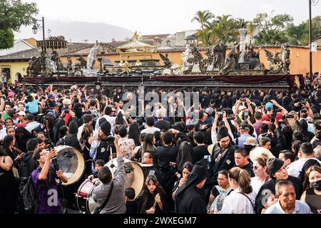 Antigua, Guatemala. März 2024. Katholische Pönitenten tragen den massiven Prozessionswagen bei der Karfreitagsprozession des Senor Sepultado Escuela de Cristo während der Semana Santa, 29. März 2024 in Antigua, Guatemala. Die opulenten Prozessionen, detailgetreuen Alfombras und jahrhundertealten Traditionen ziehen mehr als 1 Million Menschen in die alte Hauptstadt. Quelle: Richard Ellis/Richard Ellis/Alamy Live News Stockfoto