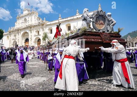 Antigua, Guatemala. März 2024. Katholische Pönitenten drehen den gewaltigen Karfreitagszug von La Merced, während sie während der Semana Santa am 29. März 2024 in Antigua, Guatemala, an der Kathedrale San Jose vorbeifahren. Die opulenten Prozessionen, detailgetreuen Alfombras und jahrhundertealten Traditionen ziehen mehr als 1 Million Menschen in die alte Hauptstadt. Quelle: Richard Ellis/Richard Ellis/Alamy Live News Stockfoto