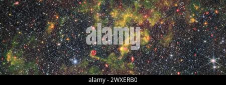 Dieses Bild zeigt die unregelmäßige Galaxie NGC 6822, die von der Nahinfrarotkamera (NIRCam) und dem Mittelinfrarotinstrument (MIRI) beobachtet wurde, die am James Webb Space Telescope montiert sind. Ein dichtes Sternenfeld mit Wolken aus Gas und Staub, die sich darüber wehen. Die Wolken sind fleckig und schräg, dichte und leuchtende Teile verdecken die Bildmitte. Helle Galaxien mit verschiedenen Formen und Größen strahlen durch das Gas und die Sterne. Einige der Sternbilder sind etwas größer als die übrigen, mit sichtbaren Beugungsspitzen; zwei Vordergrundsterne sind in der unteren rechten Ecke hell. KREDIT: NASA/ESA/CSA Stockfoto