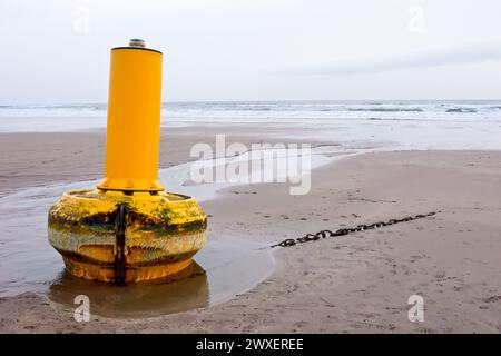 Eine gelbe Warn- oder Navigationsoje riss während eines intensiven Sturms von ihren Anlegestellen im Meer und spülte an einem Sandstrand ein paar Meilen entfernt. Stockfoto