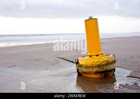 Eine gelbe Warn- oder Navigationsoje riss während eines intensiven Sturms von ihren Anlegestellen im Meer und spülte an einem Sandstrand ein paar Meilen entfernt. Stockfoto