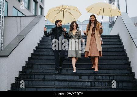 Modisches Trio, das fröhlich im Regen spaziert, mit Regenschirmen auf städtischen Treppen, die Freundschaft und Herbststil zum Ausdruck bringen. Stockfoto