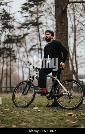 Nachdenklicher Geschäftsmann in formeller Kleidung auf einem Fahrrad im Park. Stockfoto