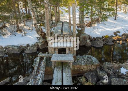 Eine kleine Holzbrücke über einen Bach zwischen zwei Seen, die zur Bewältigung der Frühlingsflut errichtet wurde. Stockfoto