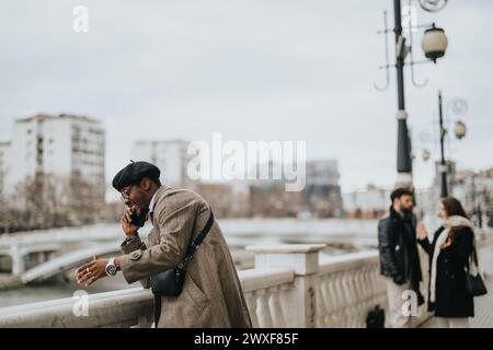 Eleganter Geschäftsmann in modischer Kleidung, der an einer Uferpromenade ein Telefongespräch führt und Selbstvertrauen und Professionalität ausstrahlt. Stockfoto