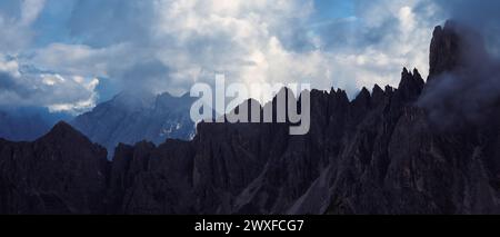 Panoramablick auf einen zerklüfteten felsigen Bergrücken in den Dolomiten, Italien, unter dramatischen Wolken und Nebel. Stimmungsvolle alpine Landschaft mit scharfen Gipfeln Stockfoto
