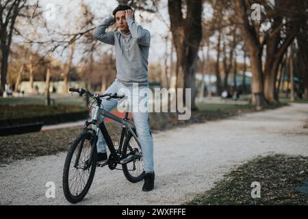 Aktiver Mann, der eine Pause mit seinem Fahrrad in einer ruhigen Park-Umgebung macht Stockfoto