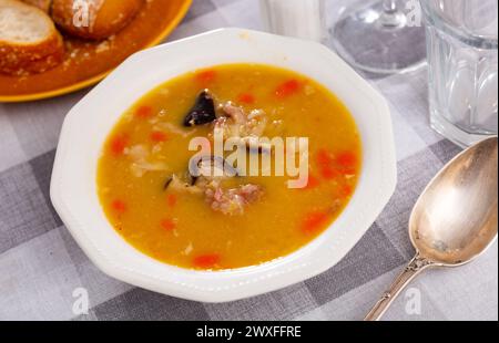 Appetitliche heiße Erbsensuppe mit geräuchertem Fleisch und Brotscheiben Stockfoto