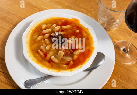 Es gibt ein traditionelles spanisches Gericht auf dem Tisch - Fabada Asturian. Dünsten Sie Suppen-Eintopf aus Bohnen, Würstchen und Gewürzen auf einem Teller Stockfoto