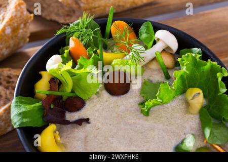 Köstliche Cremesuppe mit verschiedenen Pilzen garniert mit Karotten, Sellerie und Gemüse, serviert mit Getreidebrot. Stockfoto