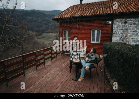 Freunde genießen ein gemütliches musikalisches Treffen auf einer rustikalen Veranda. Stockfoto
