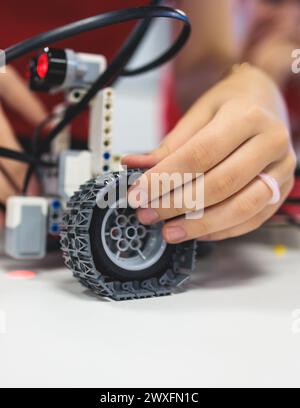 Gruppe von verschiedenen Kindern mit Roboterfahrzeugmodell, Nahaufnahme der Hände, Wissenschafts- und Ingenieurunterricht im Klassenzimmer, Herstellung, Programmierung und p Stockfoto