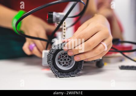 Gruppe von verschiedenen Kindern mit Roboterfahrzeugmodell, Nahaufnahme der Hände, Wissenschafts- und Ingenieurunterricht im Klassenzimmer, Herstellung, Programmierung und p Stockfoto