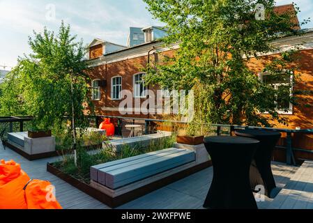 Eine moderne, urbane Dachterrasse mit stilvollen Möbeln und Grün vor dem Hintergrund eines Backsteingebäudes. Stockfoto