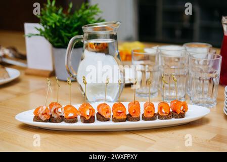 Elegante geräucherte Lachsbrötchen mit Frischkäse serviert auf mundgroßem Pumpernickelbrot, wunderschön auf einem Servierteller für ein Treffen präsentiert. Stockfoto