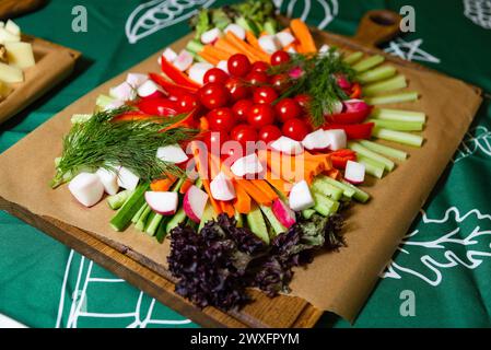 Farbenfrohe Gemüserote kunstvoll auf einem hölzernen Schneidebrett mit verschiedenen Dips für gesundes Naschen angeordnet. Stockfoto