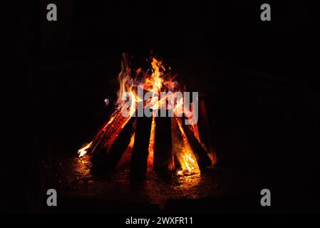 Ein warmes Lagerfeuer brennt hell vor der dunklen Kulisse der Nacht und schafft eine gemütliche Atmosphäre. Stockfoto