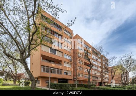 Fassaden terrakottafarbener Wohngebäude mit Gärten mit Hecken, Rasen und Bäumen Stockfoto