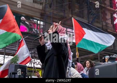 New York, Usa. 30. März 2024. Eine Frau, die eine Kefiyah trägt und von palästinensischen Fahnen flankiert wird, spricht die Menge an. Pro-palästinensische Demonstranten versammeln sich am Times Square und marschieren dann zum Land Day in den Washington Square Park. Der Tag erinnert an die Ermordung von sechs Palästinensern, die gegen die Beschlagnahme palästinensischer Gebiete durch israelische Truppen im Jahr 1976 protestierten. Quelle: SOPA Images Limited/Alamy Live News Stockfoto