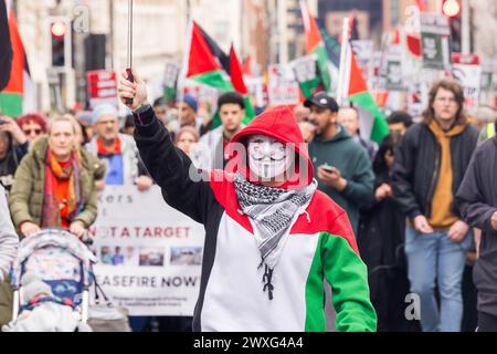 Leeds, Großbritannien. 30. MÄRZ 2024. Pro-palästinensische Demonstranten, darunter ein Demonstrant mit anonymer Maske, marschieren die Headrow entlang auf dem Weg durch das Zentrum von Leeds. Die Route begann und endete in der Leeds Art Gallery, wobei sie die Boar Lane und The Headrow hinunterfuhr, ohne dass es Ärger gab. Credit Milo Chandler/Alamy Live News Stockfoto