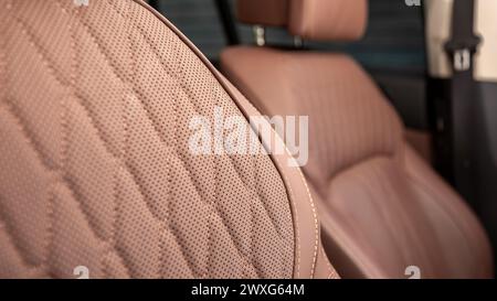 Teil der Ledersitze mit Kopfstützen für Autos. Сlose-up brauner, perforierter Ledersitz. Hautstruktur Stockfoto