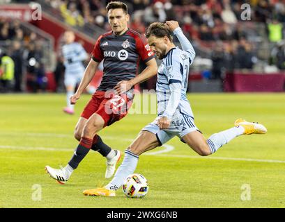 Toronto, Kanada. 30. März 2024. Tim Leibold (R) von Sporting Kansas City schießt den Ball beim Major League Soccer (MLS) Spiel 2024 zwischen Toronto FC und Sporting Kansas City auf dem BMO Field in Toronto, Kanada, 30. März 2024. Quelle: Zou Zheng/Xinhua/Alamy Live News Stockfoto