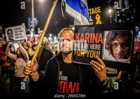 Tel Aviv, Israel. 30. März 2024. Ein Demonstrant hält ein Plakat mit dem Foto von Karina Ariev, 19, die von der Hamas in Gaza als Geisel gehalten wird, während eines Protestes in Tel Aviv am Samstag, dem 30 2024. März. Am Samstag waren Zehntausende in ganz Israel zum größten Protest seit dem 7. Oktober gegen die aktuelle Regierung unter Premierminister Benjamin Netanjahu und verlangten einen Geiselvertrag mit der Hamas. (Foto von Eyal Warshavsky/SOPA Images/SIPA USA) Credit: SIPA USA/Alamy Live News Stockfoto