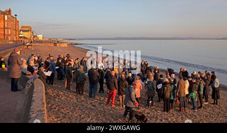 Portobello, Edinburgh, Schottland, Großbritannien. 31. März 2024. Atemberaubender Sonnenaufgang im britischen Sommer an der schottischen Küste sowie Ostersonntag. Im Bild: Mitglieder der Pfarrkirche Portobello Joppa versammeln sich bei Sonnenaufgang, um Lieder zu singen und am Ostermorgen willkommen zu heißen. Quelle: Arch White/Alamy Live News. Stockfoto