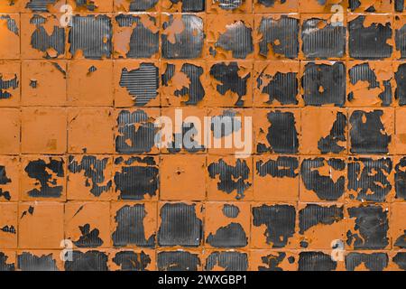 Alte abblätternde, gerissene orangefarbene Farbe mit grauem Hintergrund aus Glas. Stockfoto