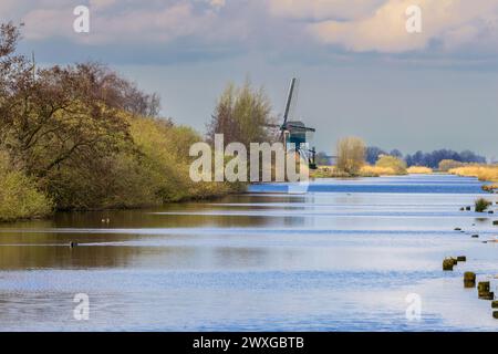 Landschaft mit Deich und historischem Oukoopse molen mit miller's Cottage entlang der Enkel Wiericke in der niederländischen Provinz Zuid Holland gegen einen Hinterhalt Stockfoto