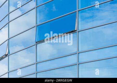 Blaues Glas reflektiert den bewölkten Himmel, moderne Gebäudefassade, Außenfassade, Bürotextur Hintergrund. Stockfoto