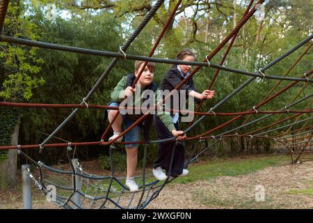 Ein Teenager-Junge und ein Mädchen klettern auf eine Spinnennetzfahrt bei einem Spaziergang im Park. Stockfoto