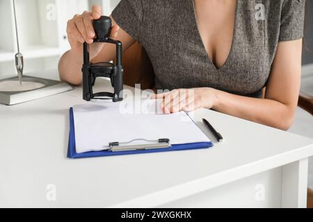 Hübsche Geschäftsfrau, die in einem Büro Stempel auf die Zwischenablage legt Stockfoto