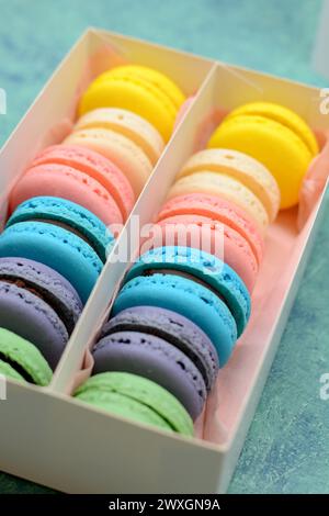 Buntes Dutzend Macarons in einer Schachtel mit blauem Band Stockfoto